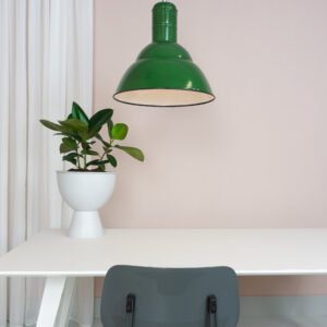 groen emaille fabriekslamp boven een witte tafel