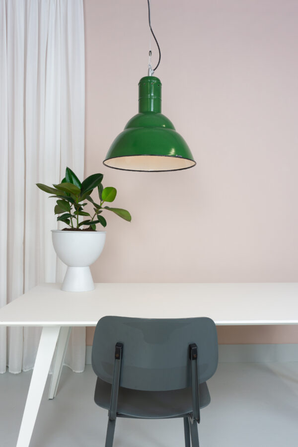 groen emaille fabriekslamp boven een witte tafel